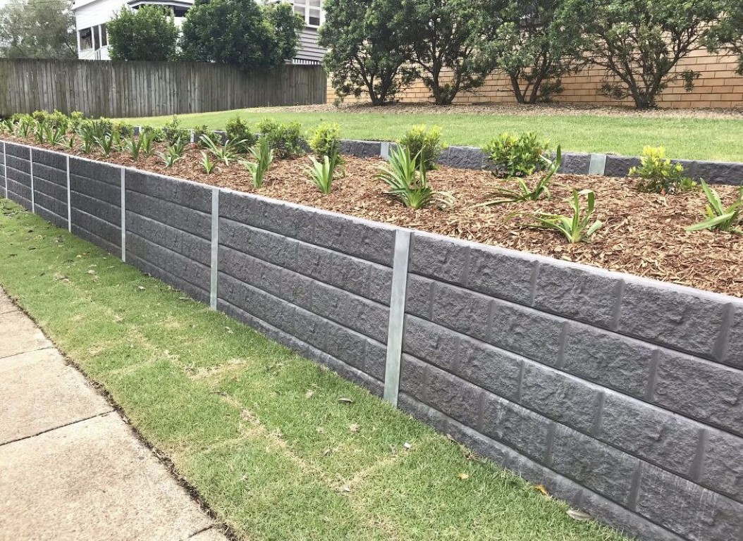 Concrete retaining wall holding back landscaping on a sloped yard in Campbell, CA